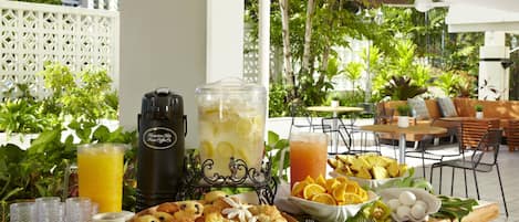 Un bufé de desayuno con diversos pasteles, un frutero y una estación para bebidas.