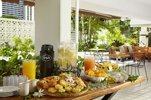 A breakfast buffet with various pastries, a fruit bowl, and a beverage station. - Oasis Hotel Waikiki (Honolulu)