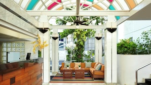 A hotel lobby with a reception desk, seating area, and a glass ceiling.