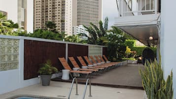 A swimming pool with lounge chairs and a view of tall buildings in the background.