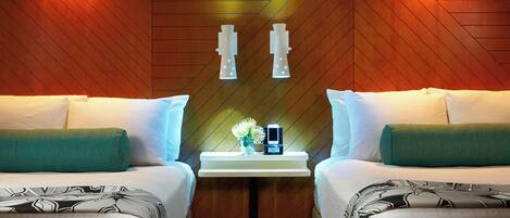 A hotel room with two beds, a nightstand with a clock and a vase of flowers, and wooden paneling on the walls.