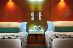 Una habitación de hotel con dos camas, una mesita de noche con un reloj y un jarrón de flores, y paneles de madera en las paredes.