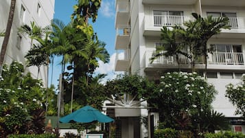 Ein mehrstöckiges Hotel mit Balkonen und einer Palme davor.