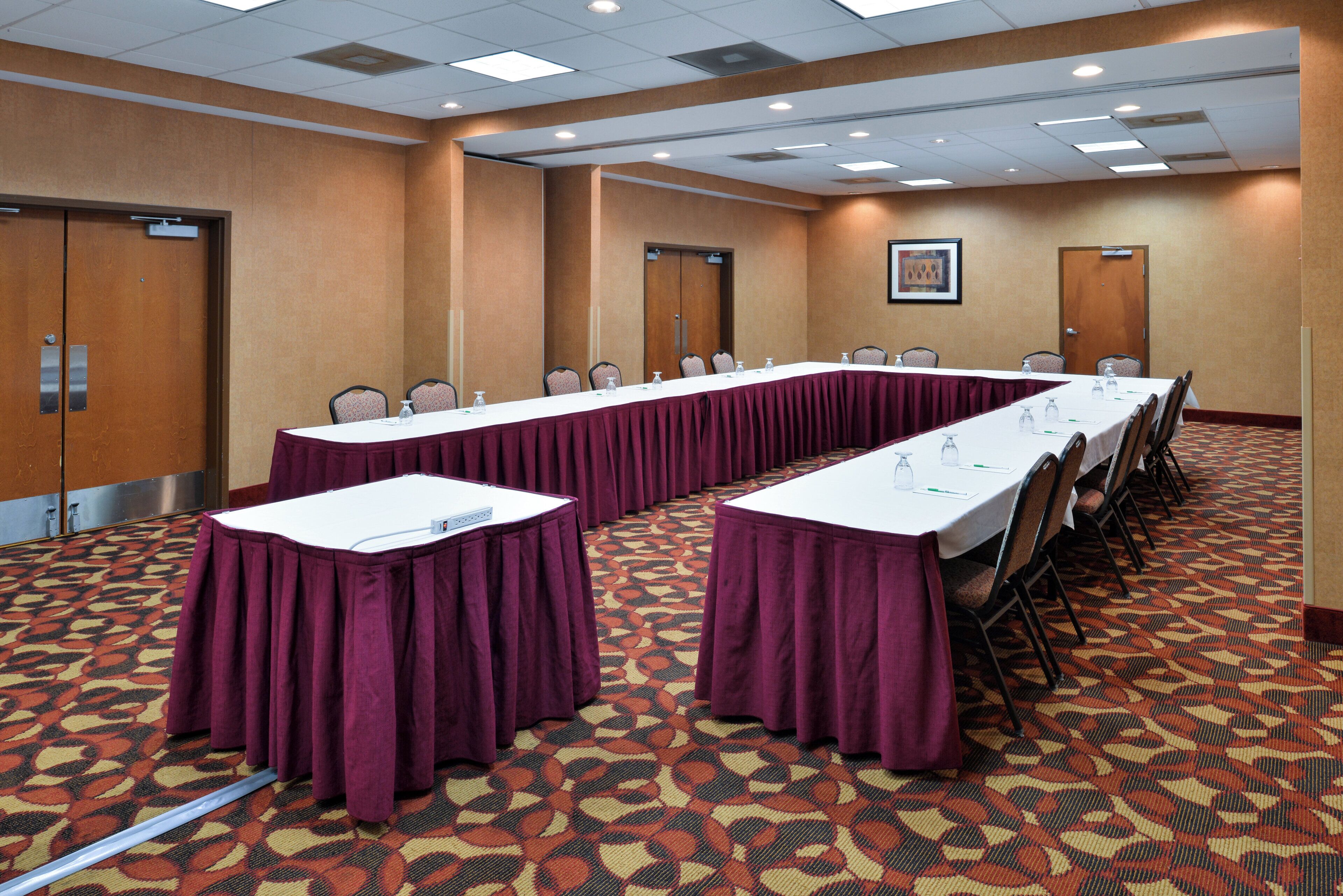 A conference room with a long table, chairs, and a patterned carpet.