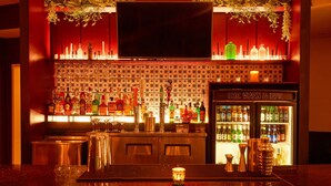 Un espace bar équipé d’un téléviseur, d’étagères remplies de bouteilles d’alcool et d’un présentoir réfrigéré.