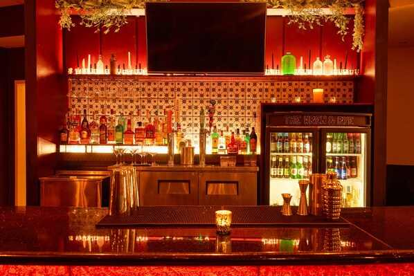 Eine Bar mit Fernseher, Regalen voller Spirituosenflaschen und einer Kühlvitrine.
