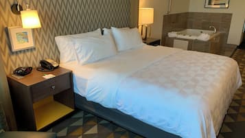 Ein Hotelzimmer mit Bett, Nachttischlampen, Telefon, einem kleinen Tisch und einem Badezimmer mit Badewanne.