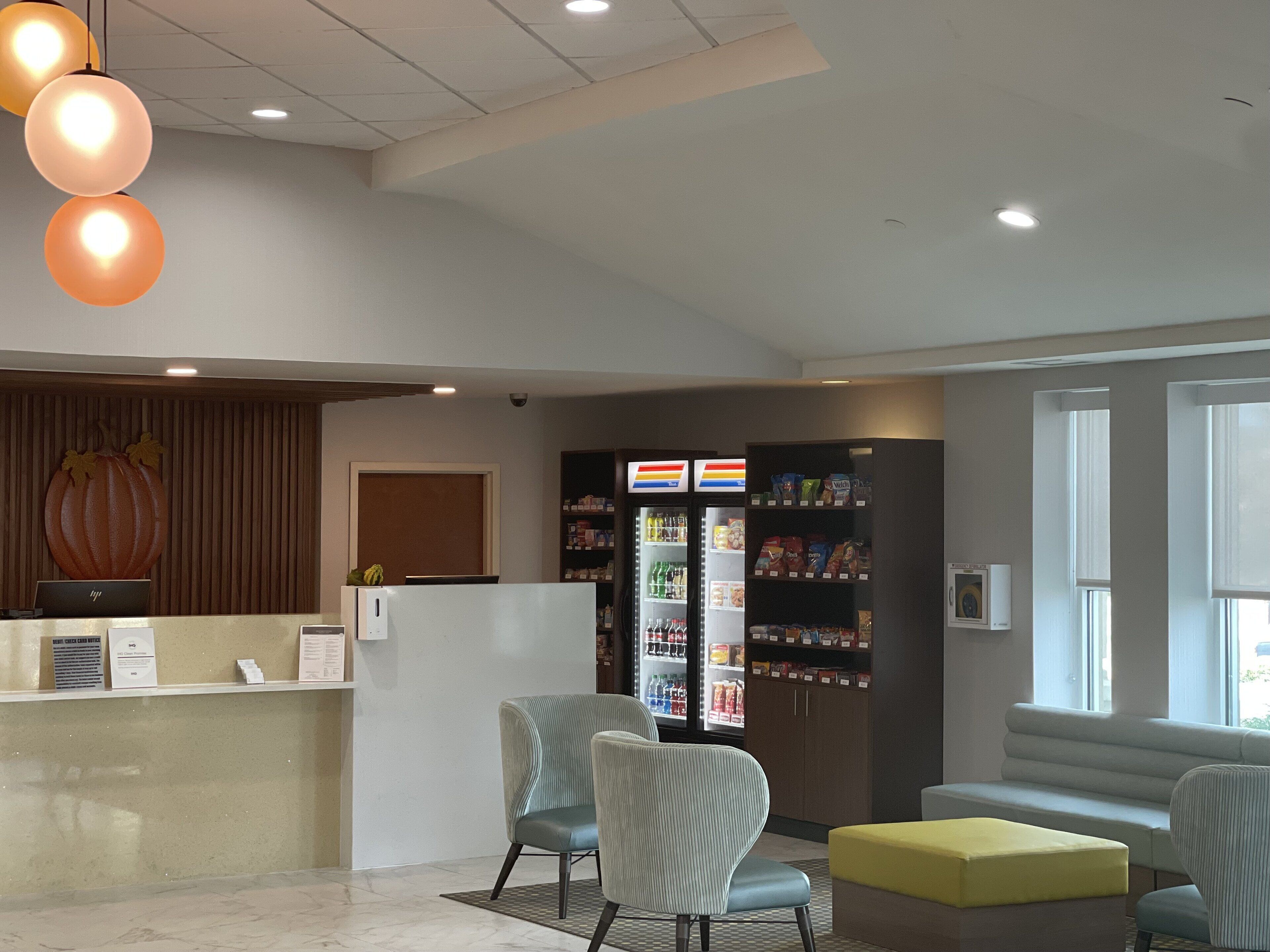 A reception area with a counter, seating, a refrigerator stocked with beverages, and a decorative pumpkin.