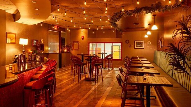 Un restaurant doté d’un bar, de plusieurs tables et chaises, ainsi que d’un espace salon avec un canapé.