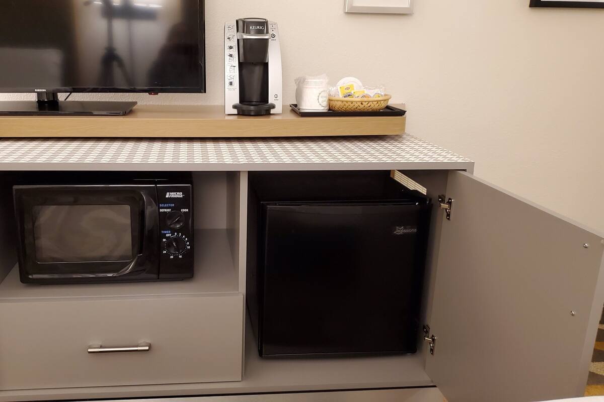 Eine kleine Küchenzeile mit einer Mikrowelle, einer Kaffeemaschine und einem Kühlschrank.