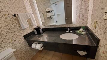 A bathroom with a black countertop, a white sink, a mirror, and a towel rack.
