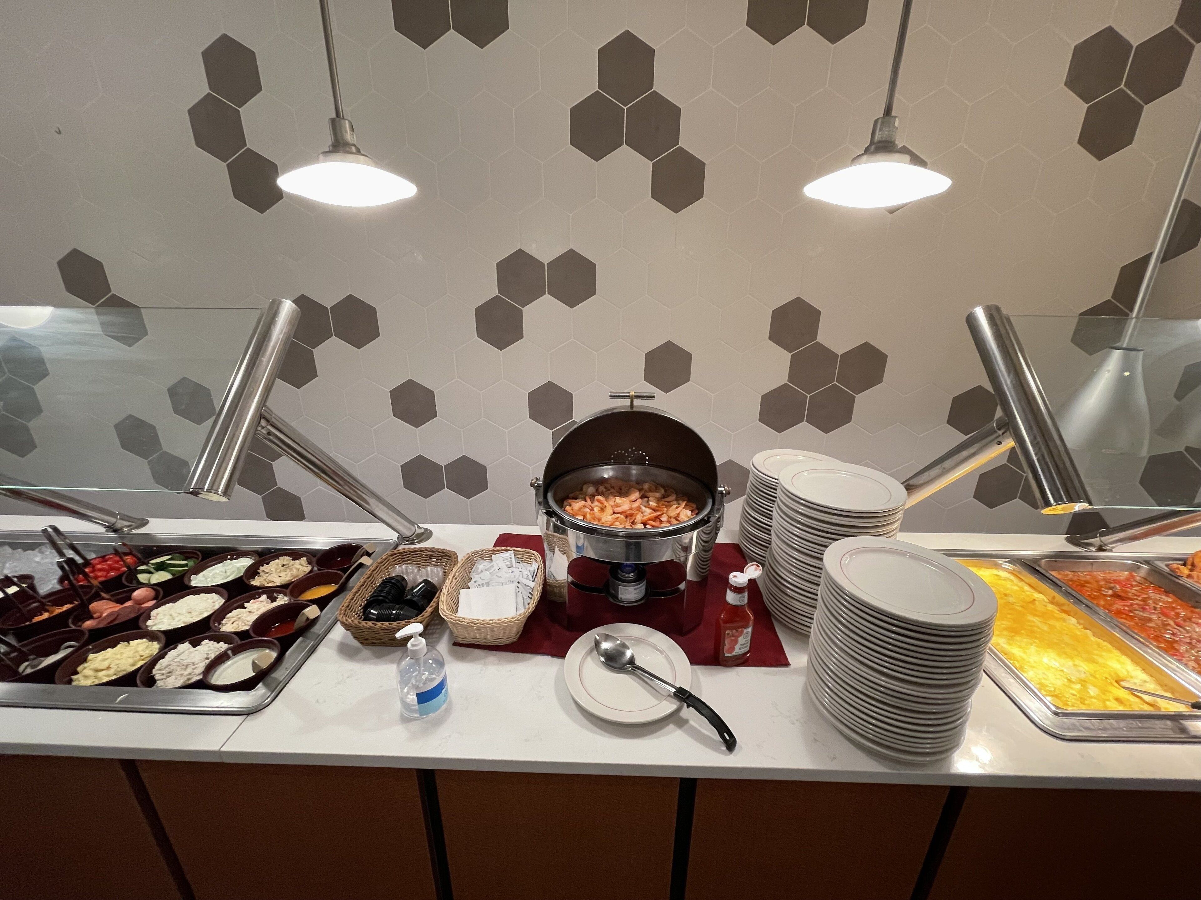 A buffet setup with various food items, a hot pot, and stacked plates.