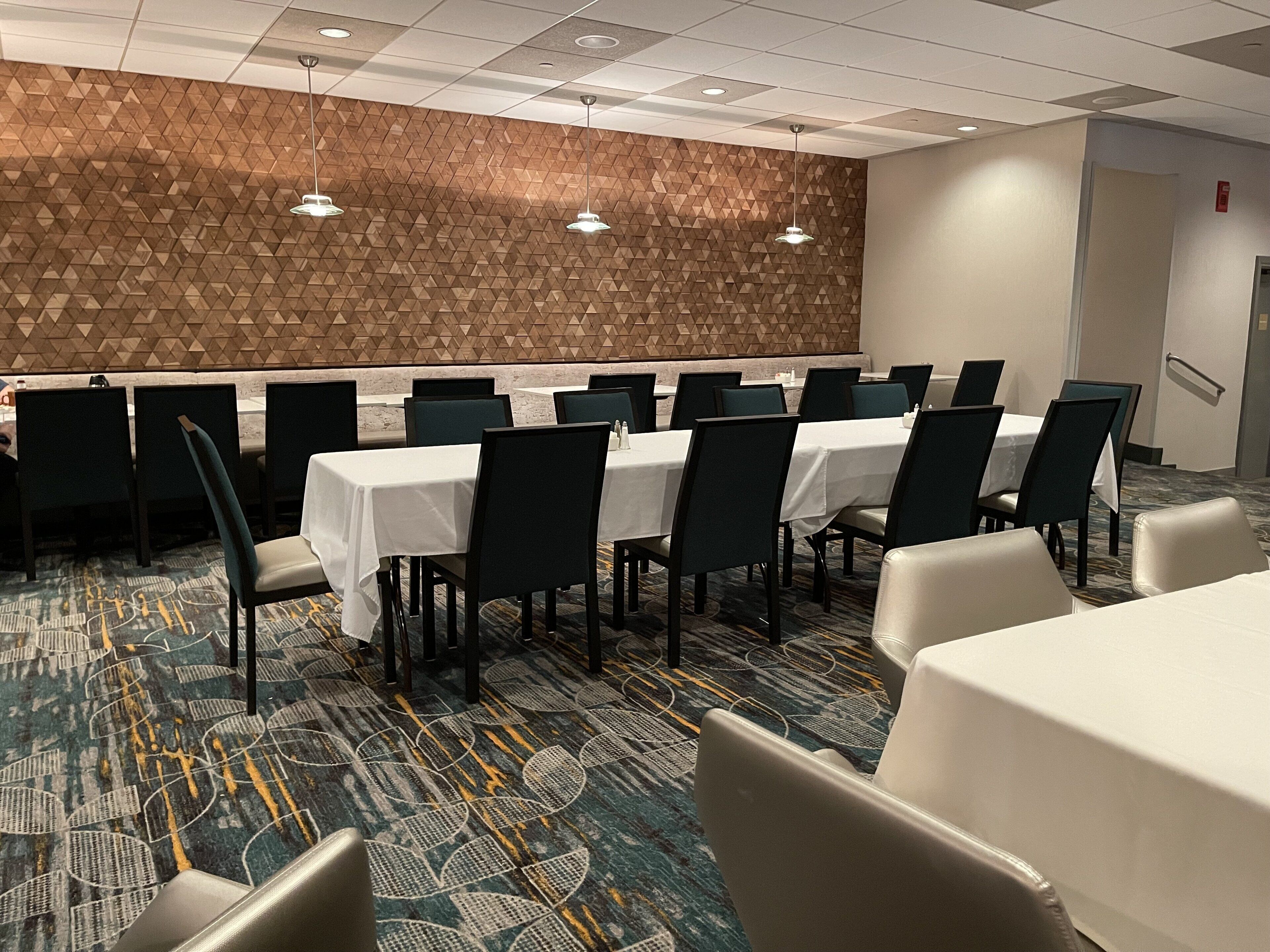 A conference room with tables and chairs, a patterned carpet, and a geometric wall design.