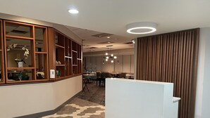 Un hall d’hôtel moderne avec un sol à motifs en chevrons, des lambris en bois et un comptoir d’accueil.