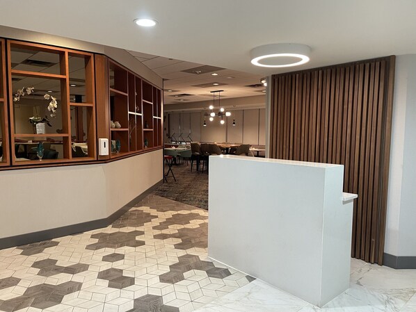 Un hall d’hôtel moderne avec un sol à motifs en chevrons, des lambris en bois et un comptoir d’accueil.