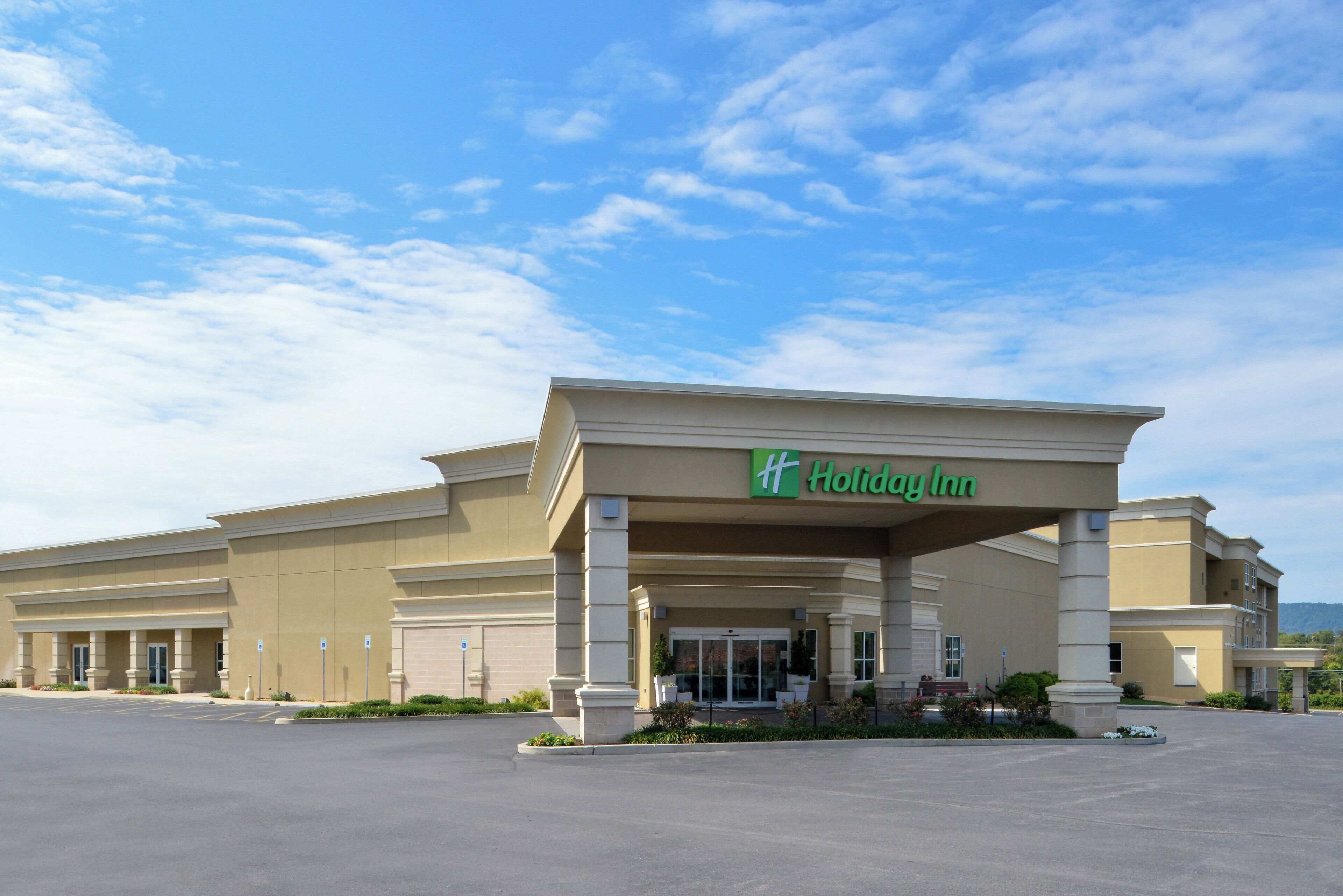 Un hôtel Holiday Inn doté d’un grand parking et offrant une vue sur un ciel dégagé.