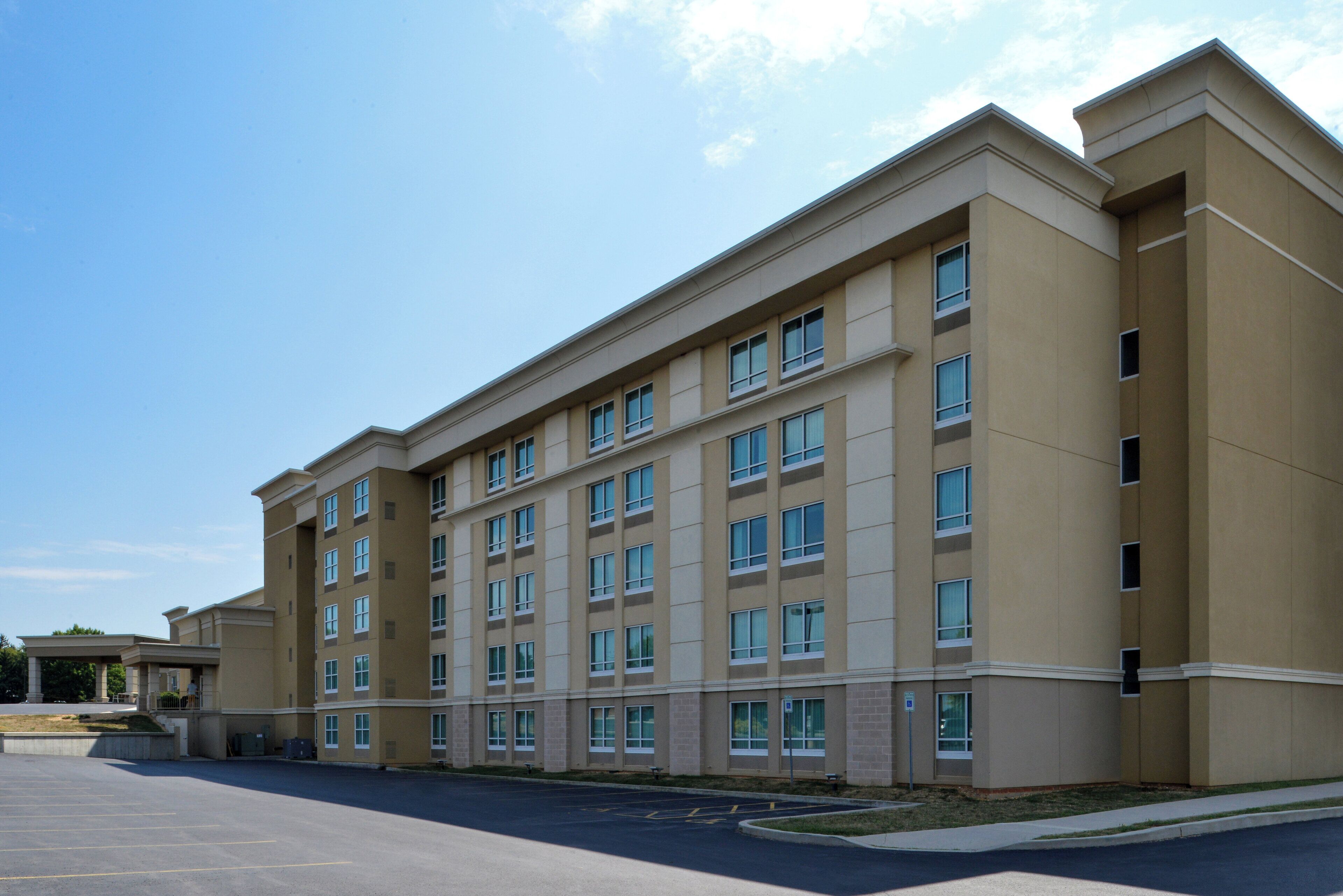 A multi-story hotel with a flat facade, large windows, and a parking lot in front.