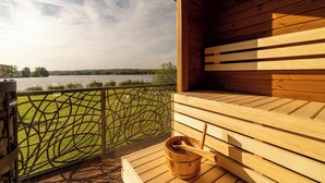 Un sauna en bois avec vue sur un lac et une clôture en métal.