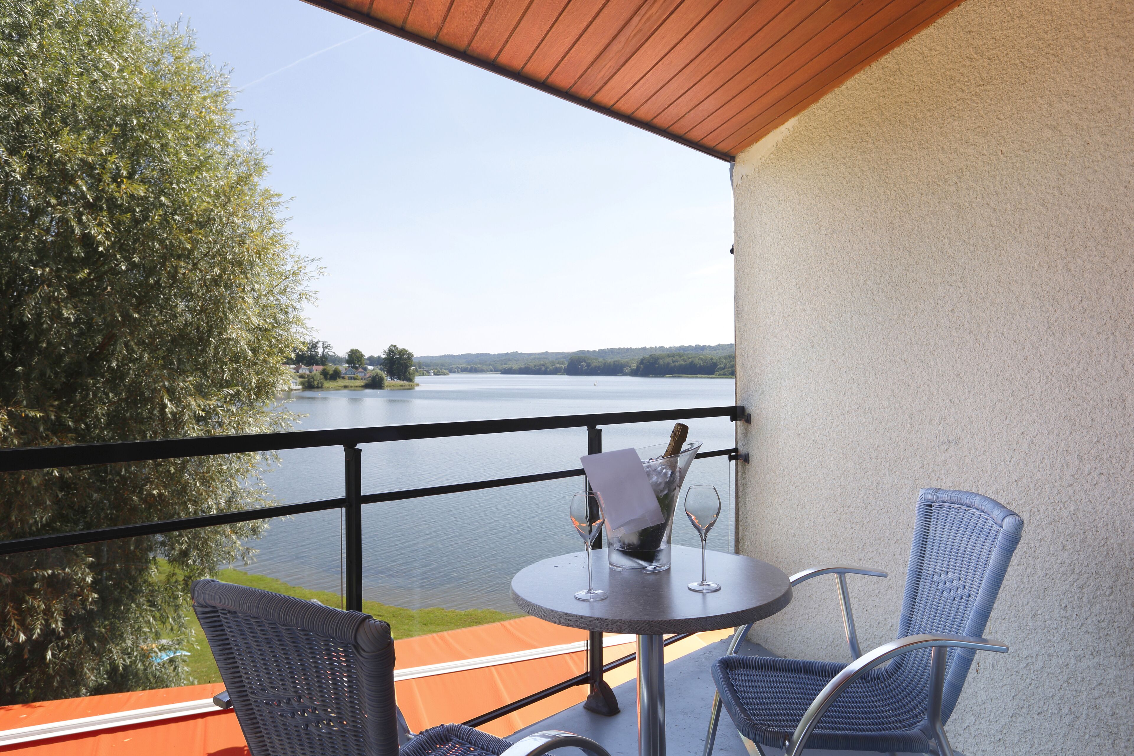 A balcony with a table, two chairs, and a bottle of champagne.