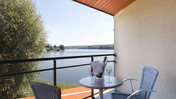 A balcony with a table, two chairs, and a bottle of champagne.