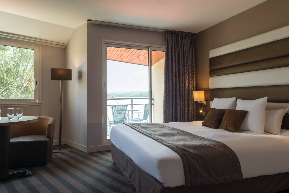 Een hotelkamer met een bed, een bureau en een balkon met uitzicht.