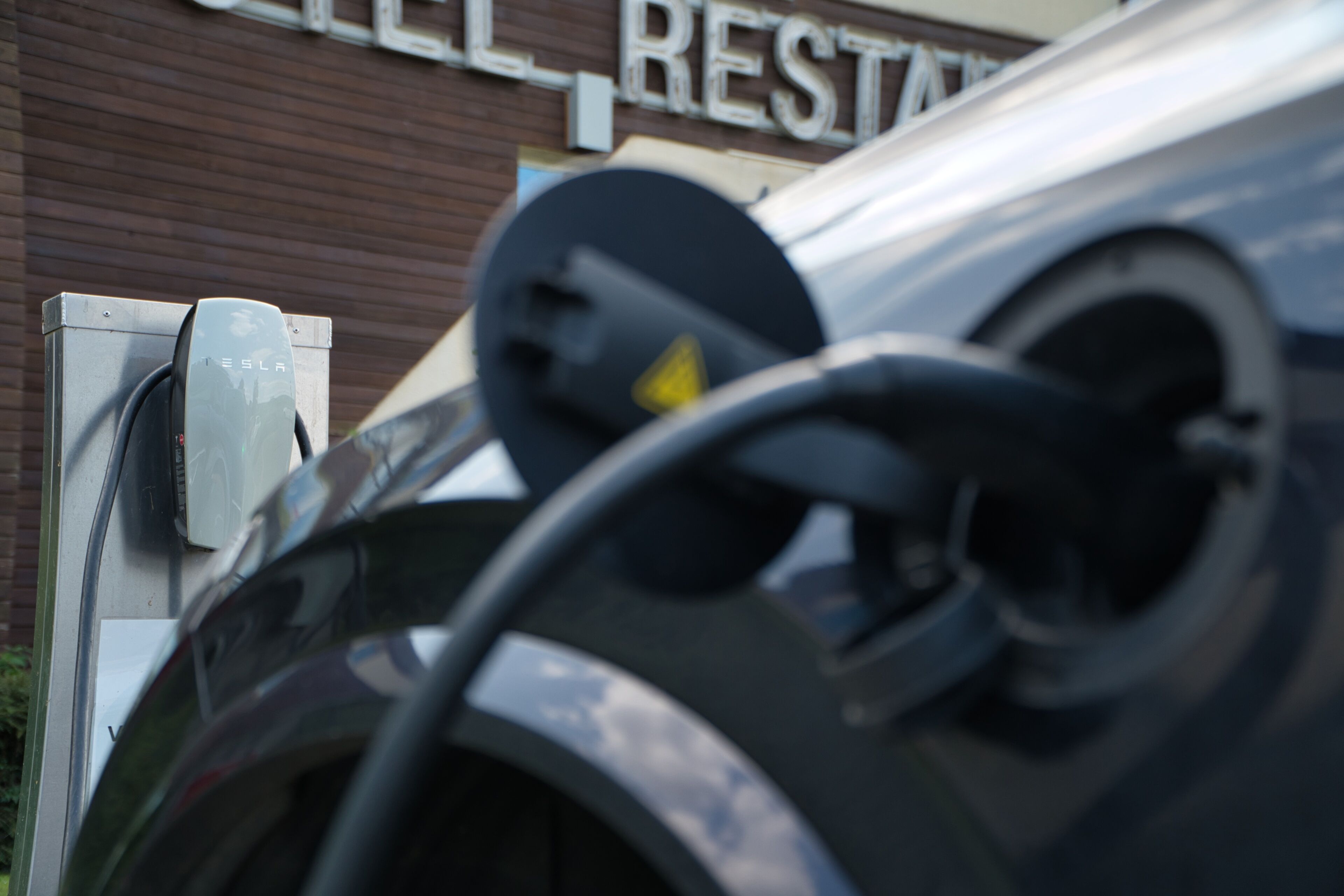 A Tesla charging station with a brick building in the background.