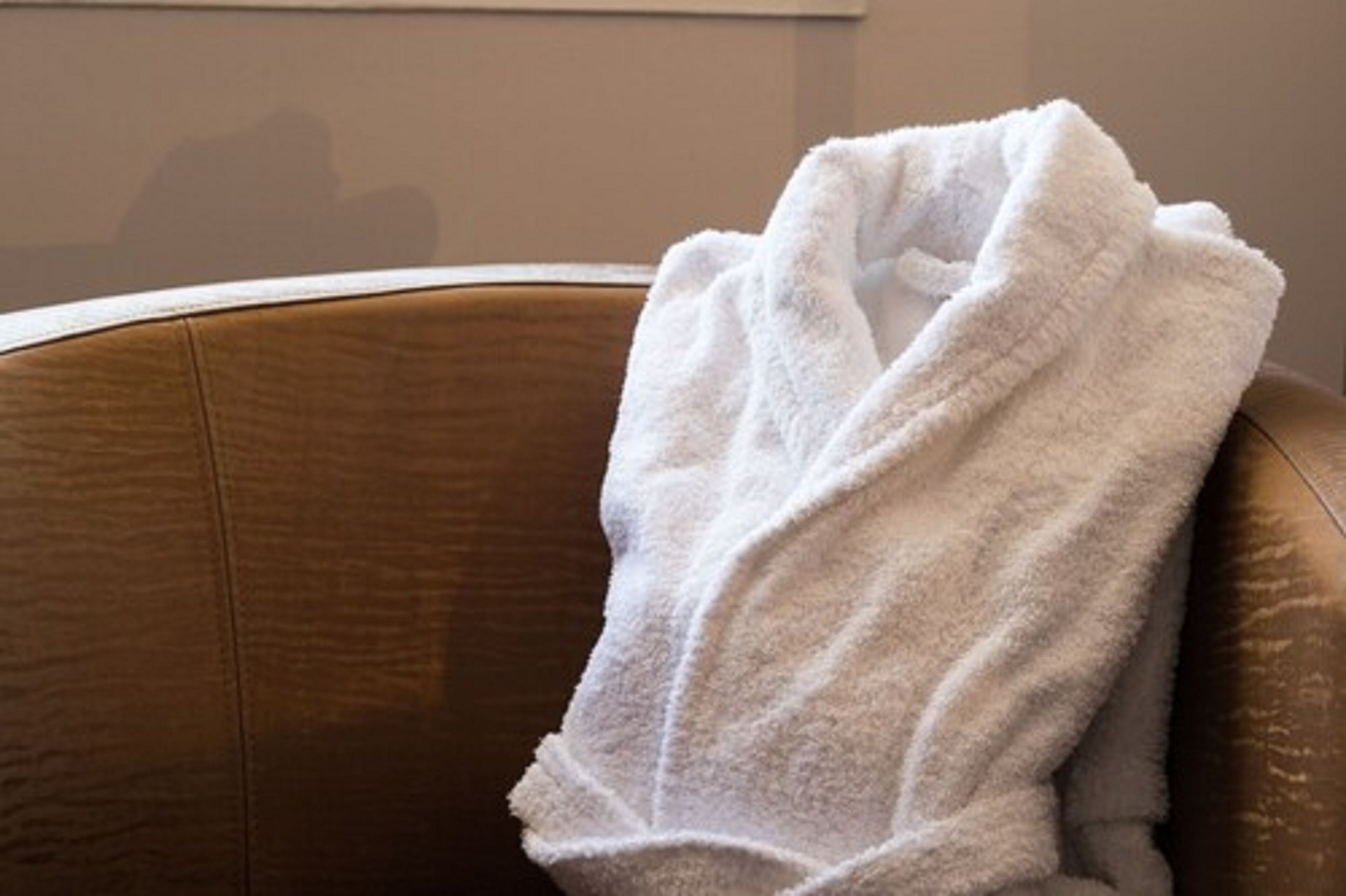 Un fauteuil en cuir marron sur lequel est posée une serviette blanche.