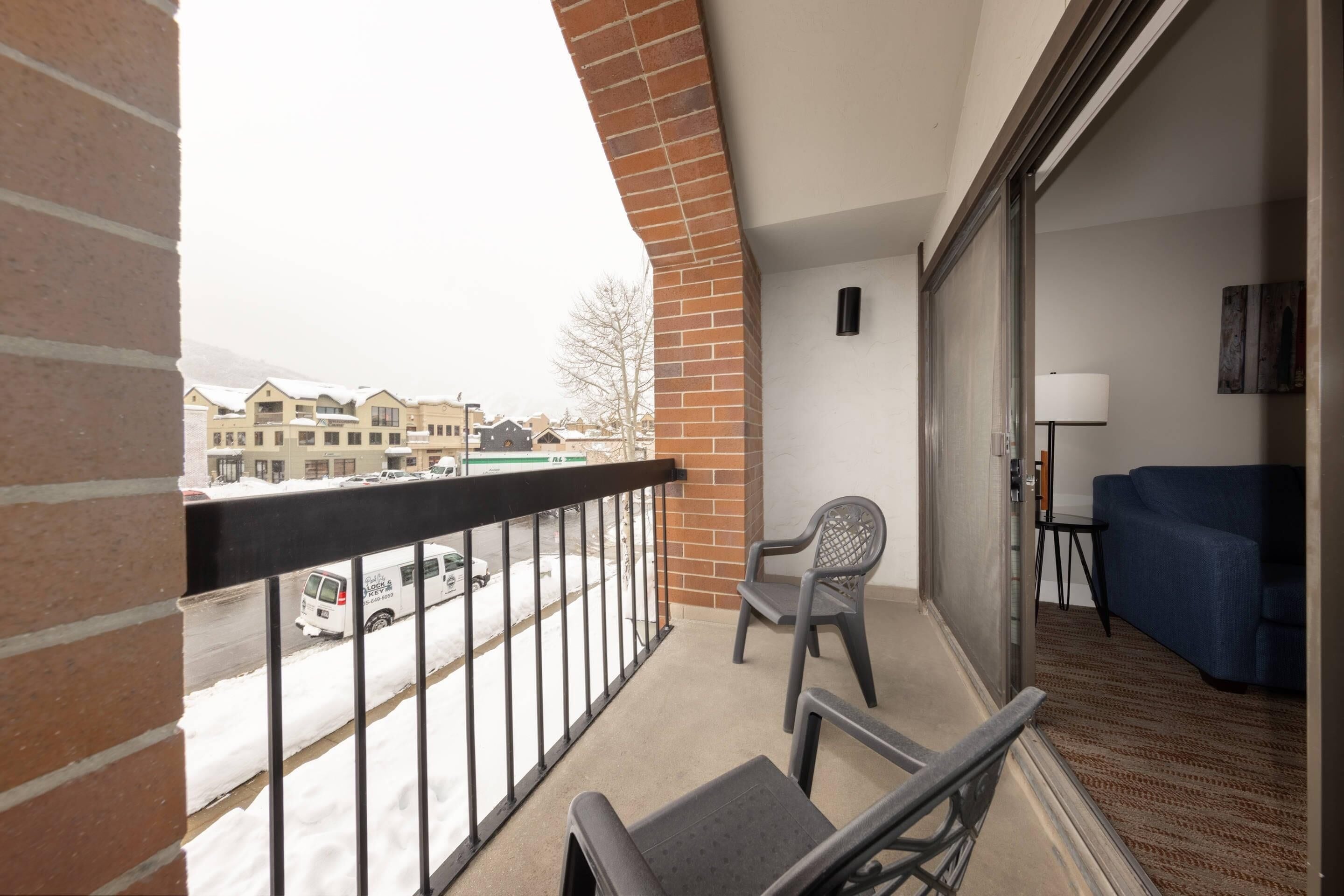 Un balcon donnant sur une rue, une chaise, un canapé et une lampe.