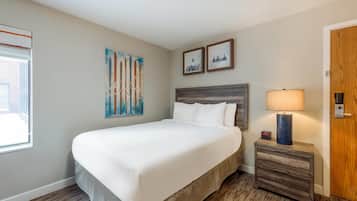A hotel room with a large bed, a nightstand with a lamp, and two framed pictures on the wall.