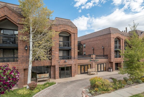 A brick building with balconies, a bench, and a sign that reads 'Sparkle'.