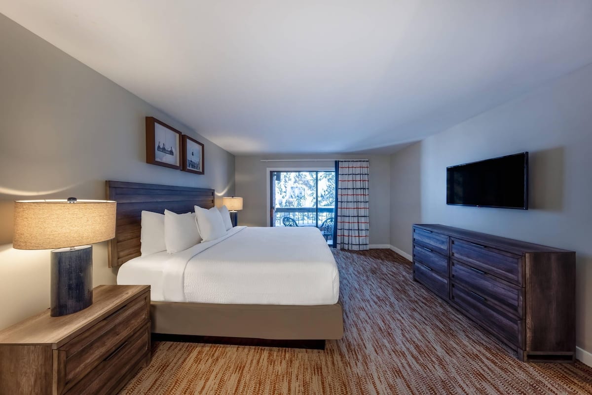 Een hotelkamer met een bed, nachtkastjes, een televisie en een raam met uitzicht.