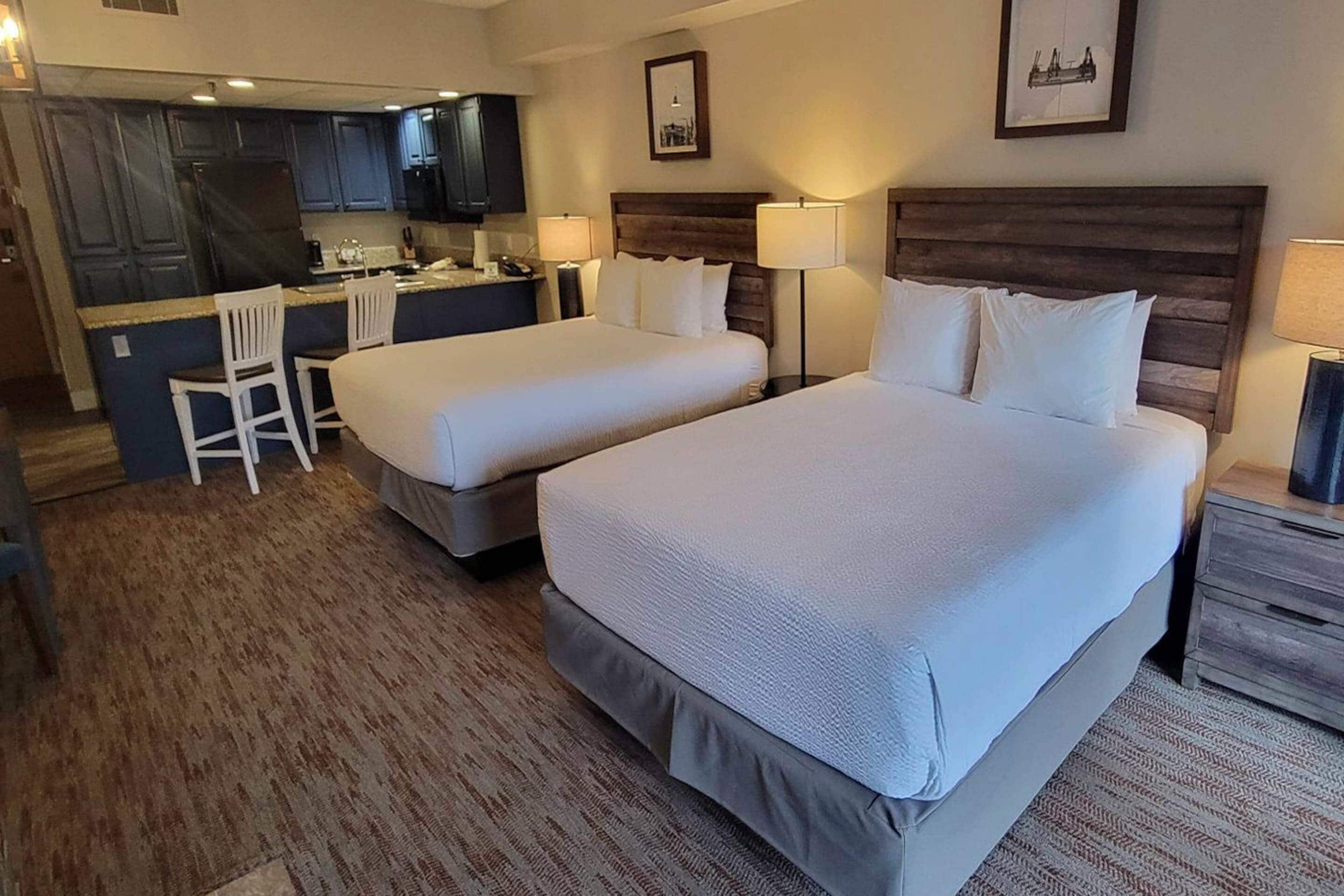 Habitación de hotel con dos camas, un escritorio y una kitchenette.