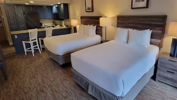 Habitación de hotel con dos camas, un escritorio y una kitchenette.
