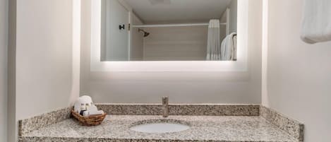 A bathroom with a granite countertop, a white sink, and a mirror above it.