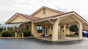 A single-story building with a covered entrance, a glass enclosure, and a parking area. - Villa Inn (Lawrenceburg)