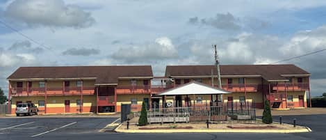 A motel with a central parking area, a covered parking structure, and a fenced playground.