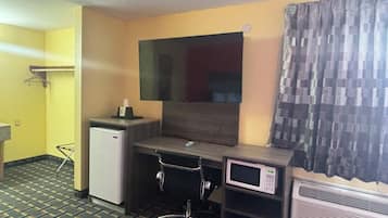 Ein kleines Hotelzimmer mit Schreibtisch, einer Mikrowelle und einer Klimaanlage.