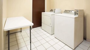 Zona de lavandería con lavadora, secadora y una mesa.