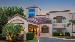 Un hotel Travelodge de estilo arquitectónico clásico, con una entrada destacada, un jardín bien cuidado y un cielo despejado.