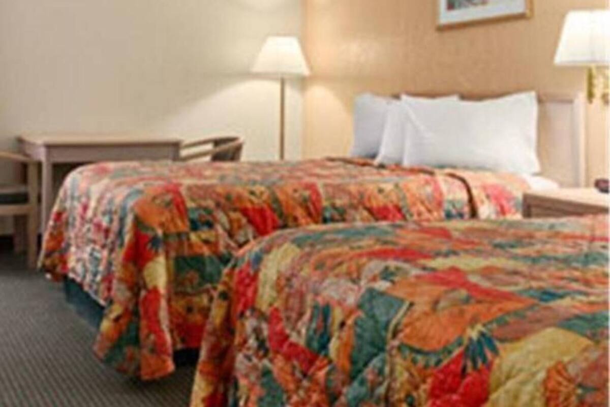 Une chambre d’hôtel avec deux lits, un bureau et une lampe.