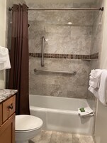A bathroom with a shower, toilet, and a towel rack.