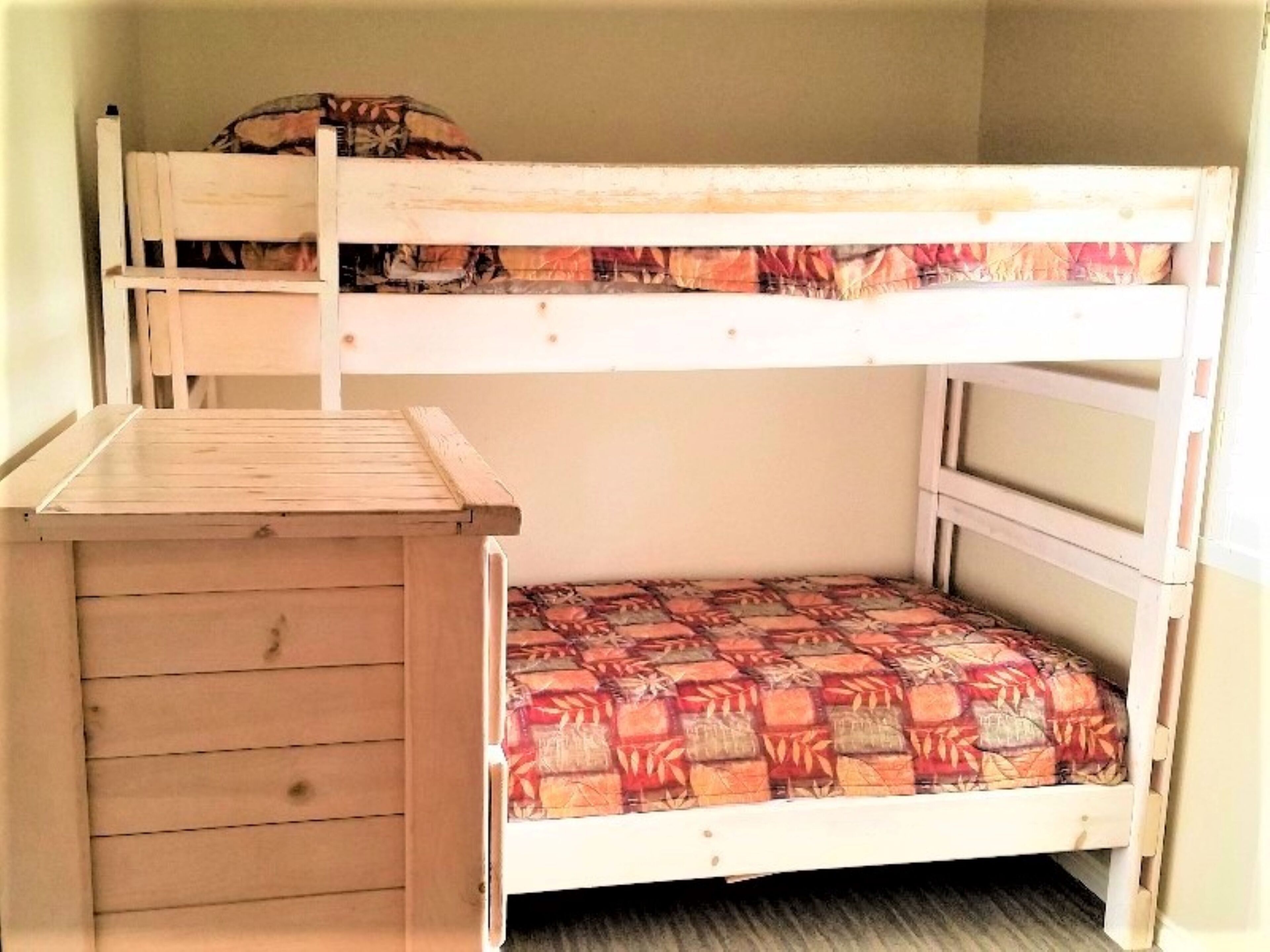 Un lit superposé avec un bureau en bois fixé au lit du bas.