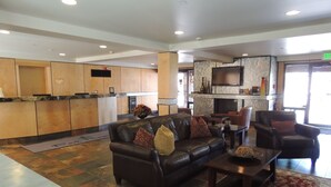 A spacious lobby with a leather sofa, a wooden reception desk, and a fireplace. - Park Regency Resort (Park City)
