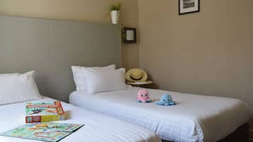 Relax in comfort with two single beds, a Monopoly game, and a cozy potted plant.