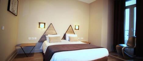 A modern hotel room with a large bed, a small table, and a chair.
