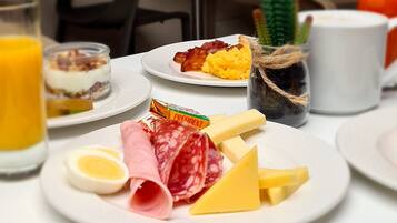 Ein Frühstückstisch mit Speisen, darunter Eier, Käse, Salami und ein Marmeladenglas.