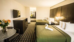 Een hotelkamer met twee bedden, een bureau, een televisie en een badkamer op de achtergrond.