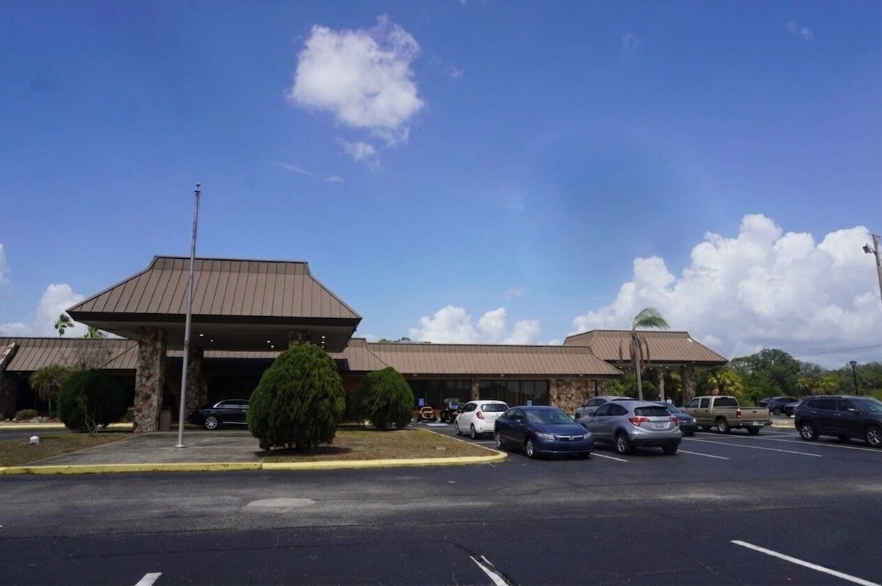 A building with a flat roof and a parking lot with several cars.