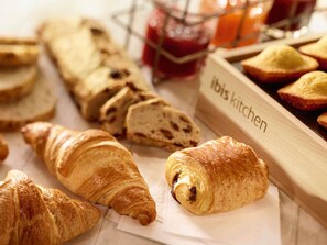 On y trouve une variété de produits de boulangerie, notamment des croissants et du pain, et un comptoir de cuisine portant l’inscription « Cuisine Ibis ».