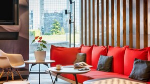 Een modern interieur met een rode bank, witte stoelen, een kleine tafel en een potplant.
